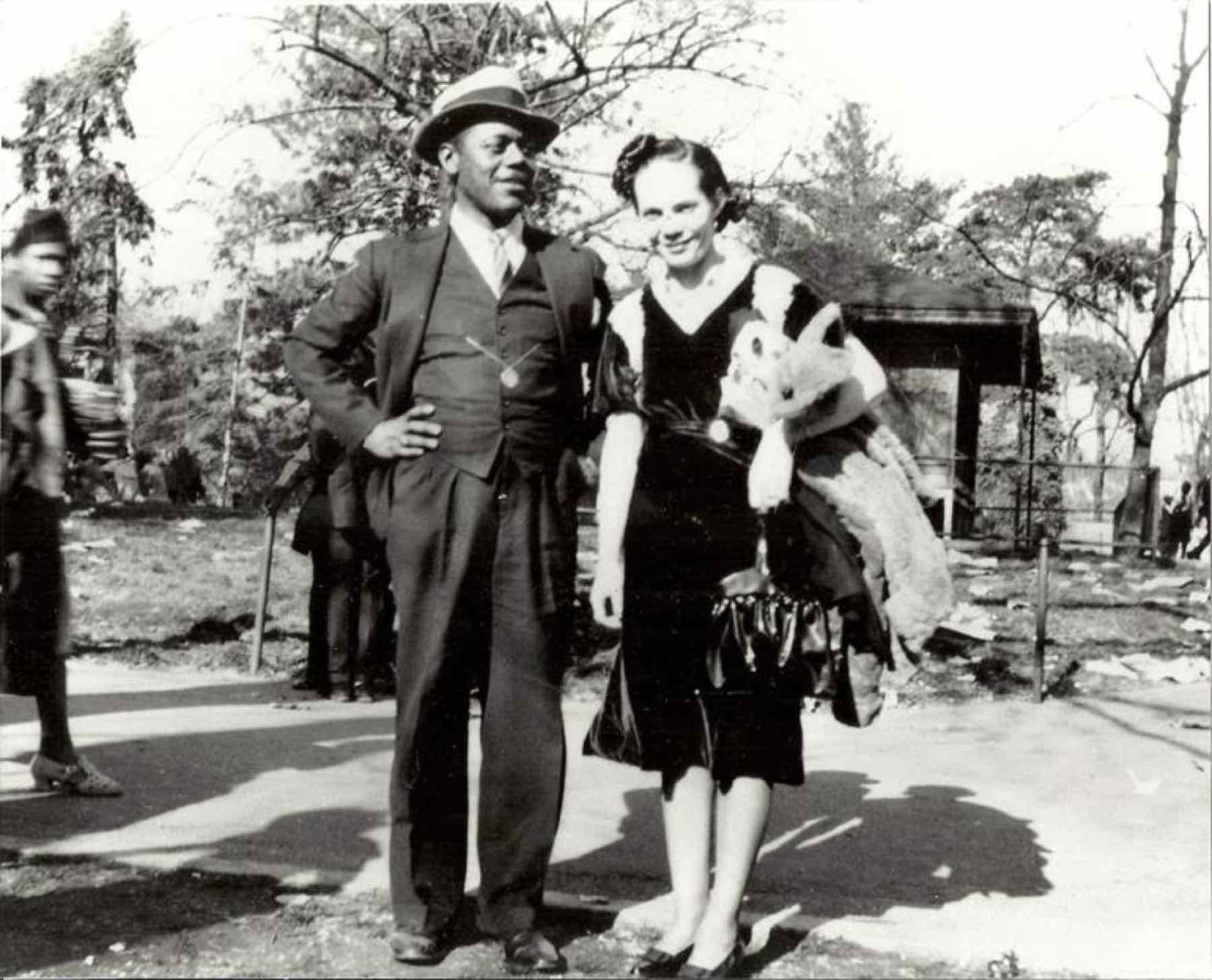 A couple photographed outdoors — the man in a three-piece suit and fedora, the woman in a dark dress with a fur stole. From the Jackson family collection; the sitters are not identified in the collection records.
